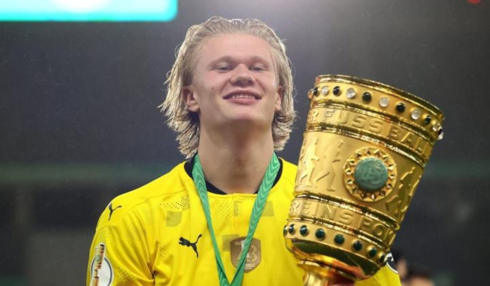 Erling Haaland celebrates in a Borussia Dortmund shirt while holding the 2021 DFB-Pokal trophy, capturing one of the defining moments of his Dortmund career